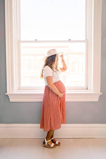 a pregnant reviewer in an orange maxi skirt