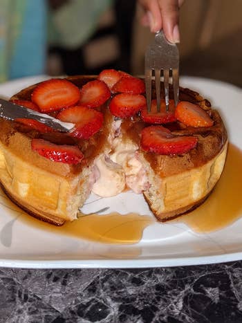 reviewer's stuffed waffle with strawberries and syrup on it