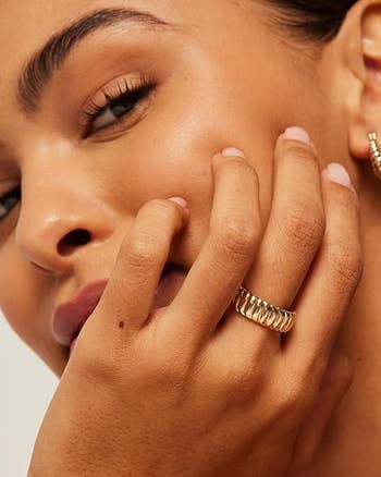 Close-up of a person showcasing a gold spiral ring,