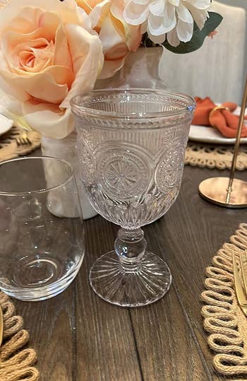 reviewer's glass on a table set for dining, with floral centerpiece and place settings