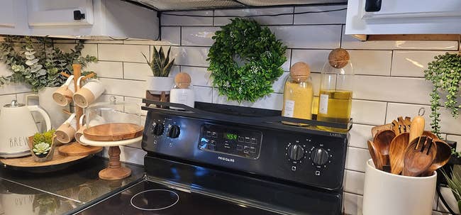 Kitchen countertop with woody utensils successful a holder, spices, decorative plants, and a stove, showcasing a cozy, organized cooking space