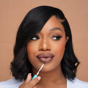 Woman applying brownish  lipstick with a soft, earthy  look