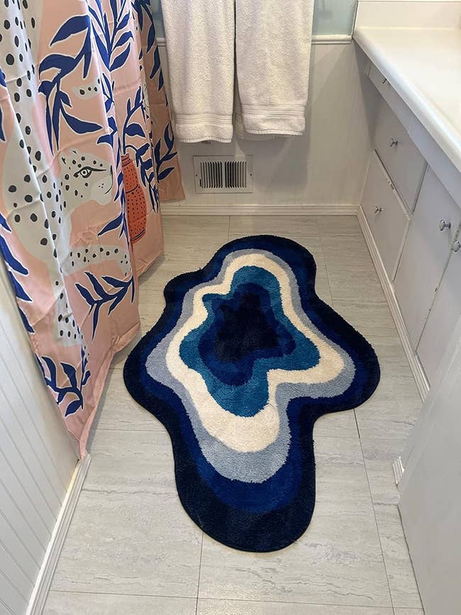 reviewer image of the blue cloud shaped rug in a bathroom