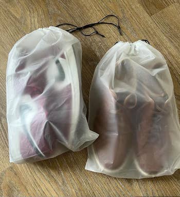 Two pairs of sneakers successful  translucent drawstring bags connected  a woody  floor, showing outlines but not circumstantial  details of the shoes