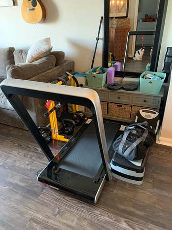 the same treadmill with the handlebar up next to couch in apartment
