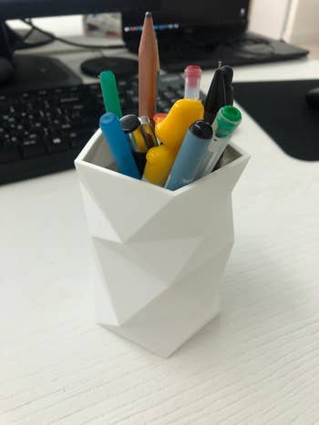another reviewer's cup holding writing utensils