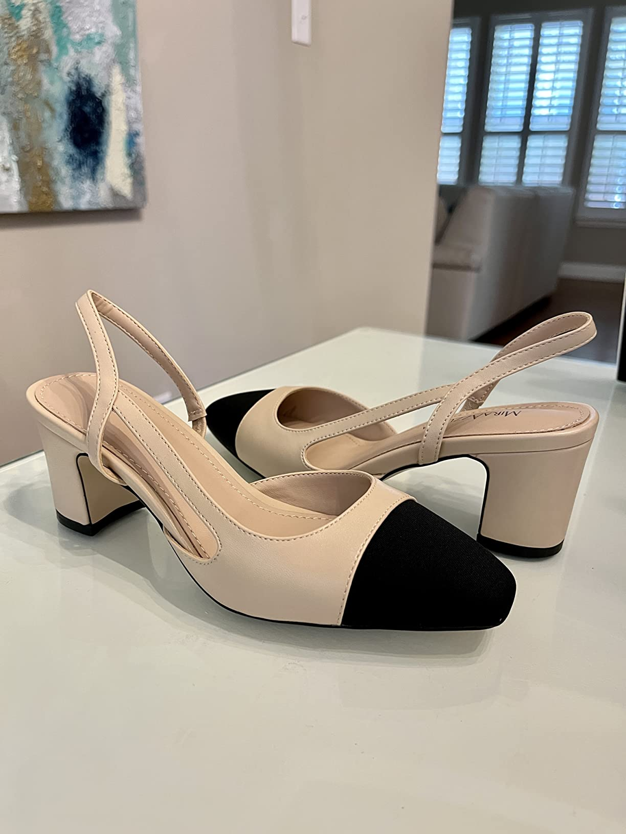 Block-heeled slingback shoes with achromatic  toed  caps connected  a show  table
