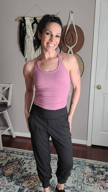reviewer in black joggers and pink tank top