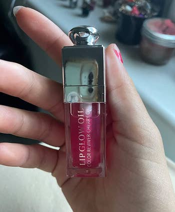 Reviewer holding a magenta lip oil 