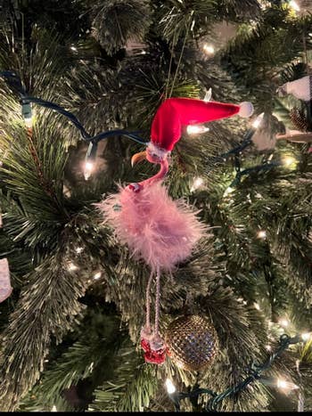 a reviewer's pink feathery flamingo ornament wearing a santa hat on a tree