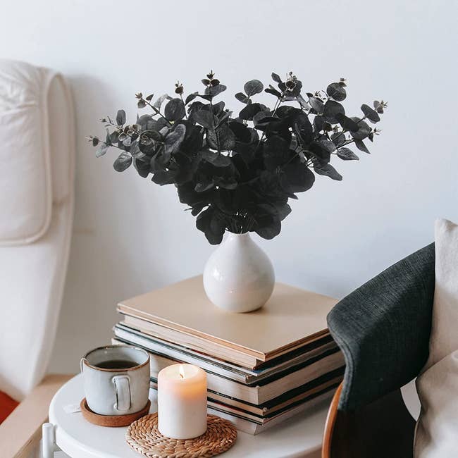 black eucalyptus bundle in vase on stack of books