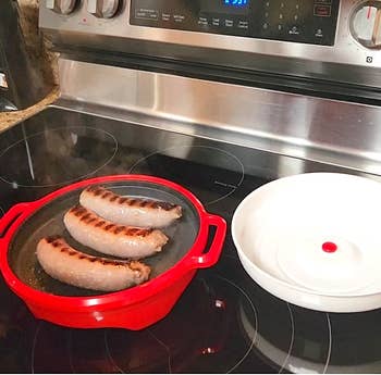 Sausages cooking successful a reddish grill cookware connected a modern stovetop, with a achromatic lid nearby. Perfect for room oregon culinary buying content