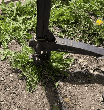 A Fiskars weeder tool being used to remove weeds from soil