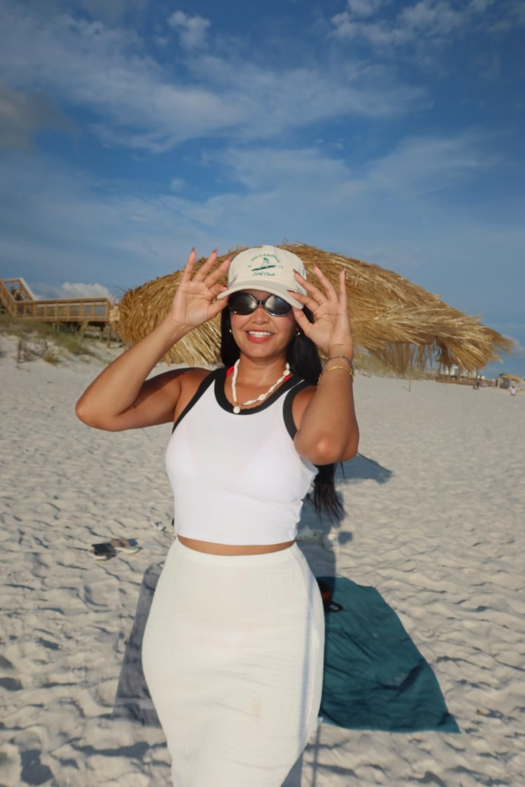 Person connected  a formation  wearing a achromatic  vessel  top, achromatic  skirt, and hat, smiling and adjusting sunglasses