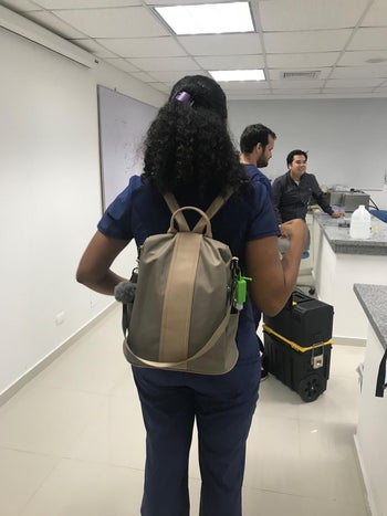 pic of reviewer wearing olive green backpack with shoulder strap and back straps