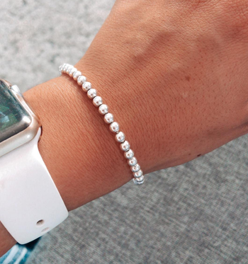 Reviewer wearing small silver beaded bracelet with smart watch