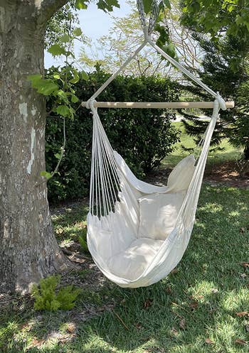a reviewer photo of the off-white hammock chair hanging from a treet 