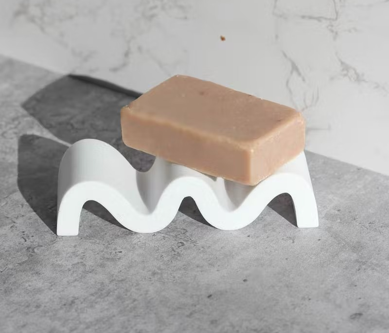 a bar of soap on top of a white wavy soap dish