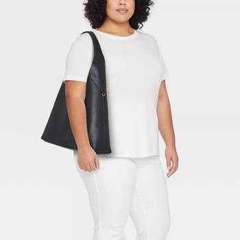 Person wearing a plain outfit with a large, sleek enarthrosis bag, suitable for a buying article