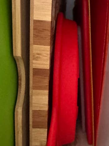 Cutting boards and reddish  trays stacked upright for organized room  storage