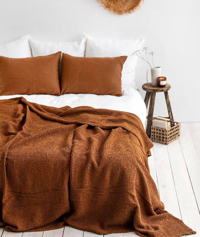 the blanket topped on a bed in a dark, orangey brown color 