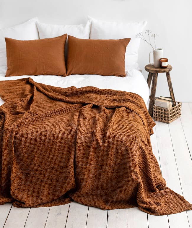the blanket topped on a bed in a dark, orangey brown color 