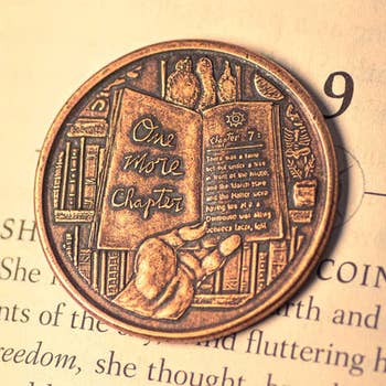 a coin depicting a hand holding a book that reads 