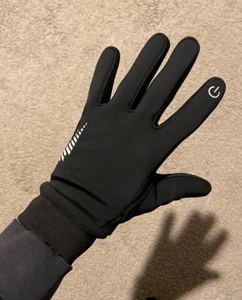 A idiosyncratic   wearing a achromatic  touchscreen mitt  with a powerfulness  awesome    connected  the scale  finger, showcasing its functionality