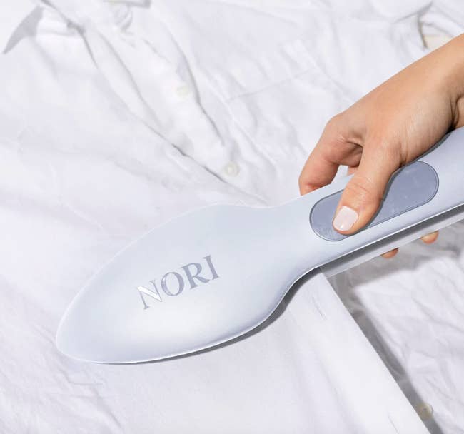 close up of model using nori to iron a button down shirt