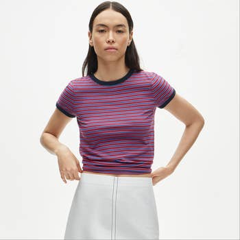 Person wearing a fitted striped t-shirt and a sleek, minimalist skirt, suitable for casual buying outings