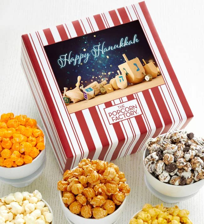 box with hanukkah decorations and five small portions of different flavored popcorn beside it