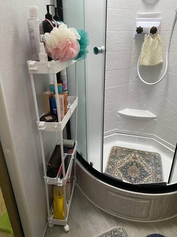 Shower country  with country   organizer holding bath essentials similar  lotions, sponges, and vessel  products. Curved ablution  doorway  leads to a tiny  rug