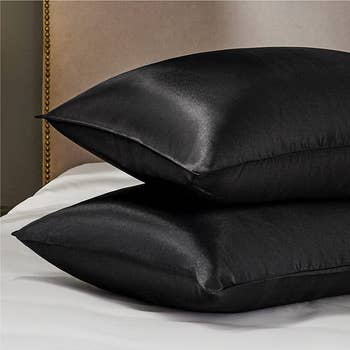 two pillows with black satin pillowcases on them