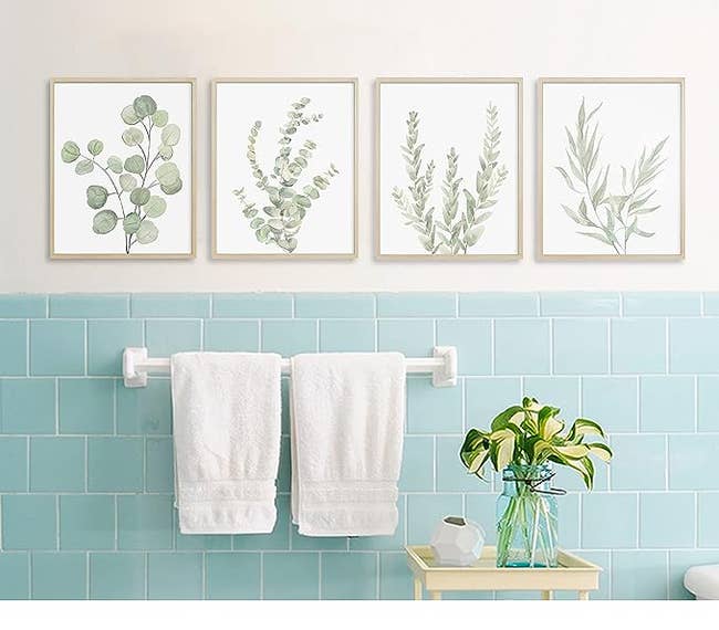 The prints hung on a bathroom wall with blue tile