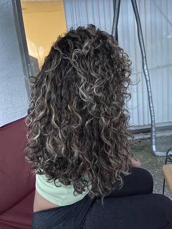 Person with long, curly hairsbreadth  seated indoors
