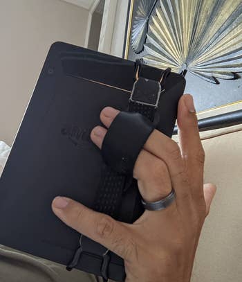 a back view of a reviewer holding a kindle using the strap