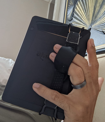 a back view of a reviewer holding a kindle using the strap