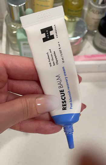 Reviewer holding small tube of repair cream 