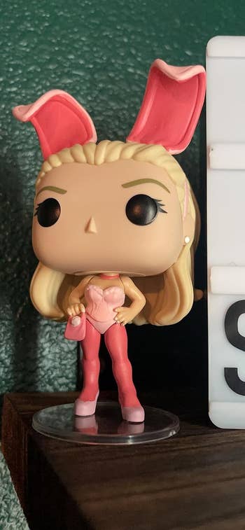 A Funko Pop figure of elle woods in a bunny costume with pink ears, long hair, and holding a cocktail glass