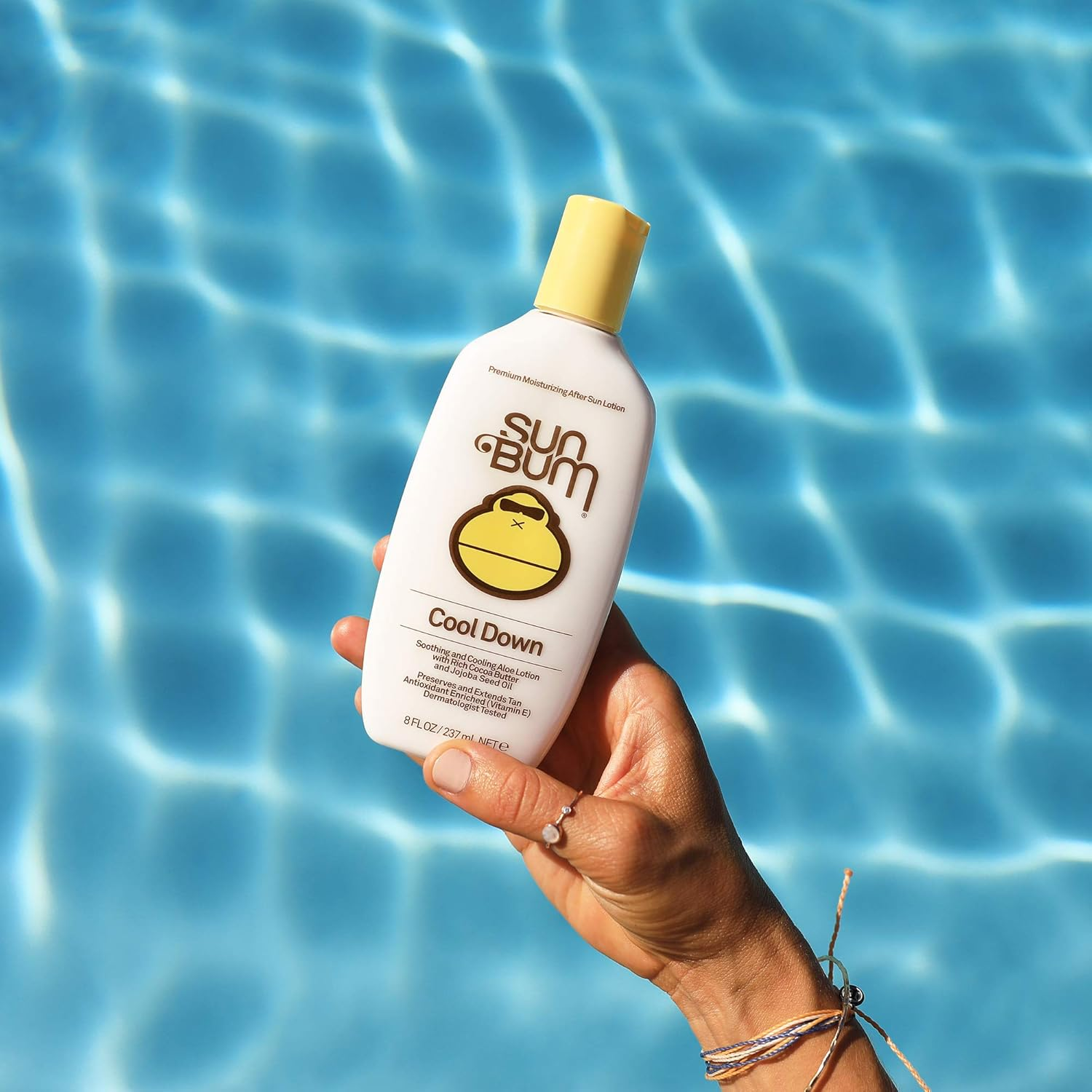 Tangan Memegang Bum Sun Cool Down Lotion di dekat kolam