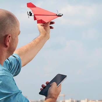 Person holding a smartphone and launching a small, high-tech insubstantial  airplane drone outdoors