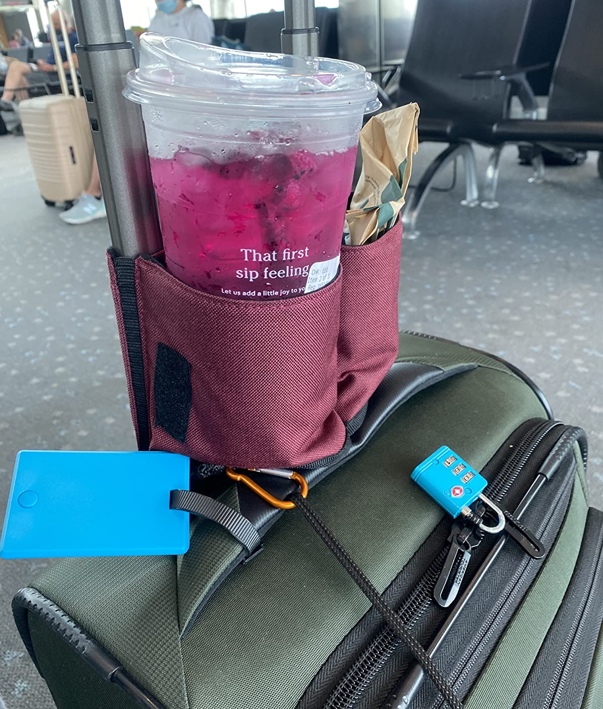 reviewer image of the cup holder attached to a suitcase with a Starbucks drink in it