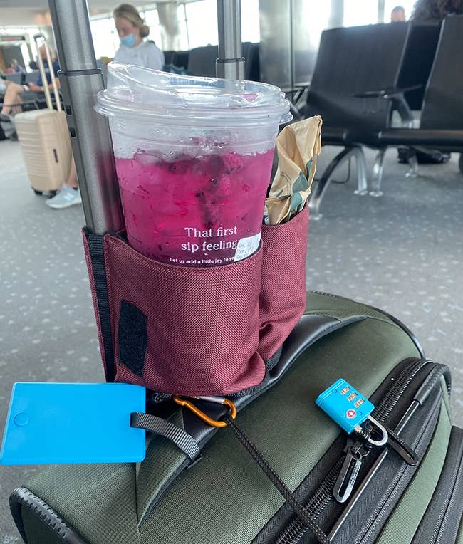 reviewer image of the cup holder attached to a suitcase with a Starbucks drink in it