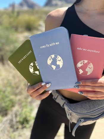 person holding three of the passport holders in different colors