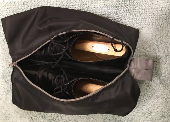 a reviewer photo of an open travel shoe bag with a pair of dress shoes inside 