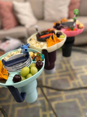 Snack trays with cup holders filled with various snacks like grapes, chips, and candies arranged on a table