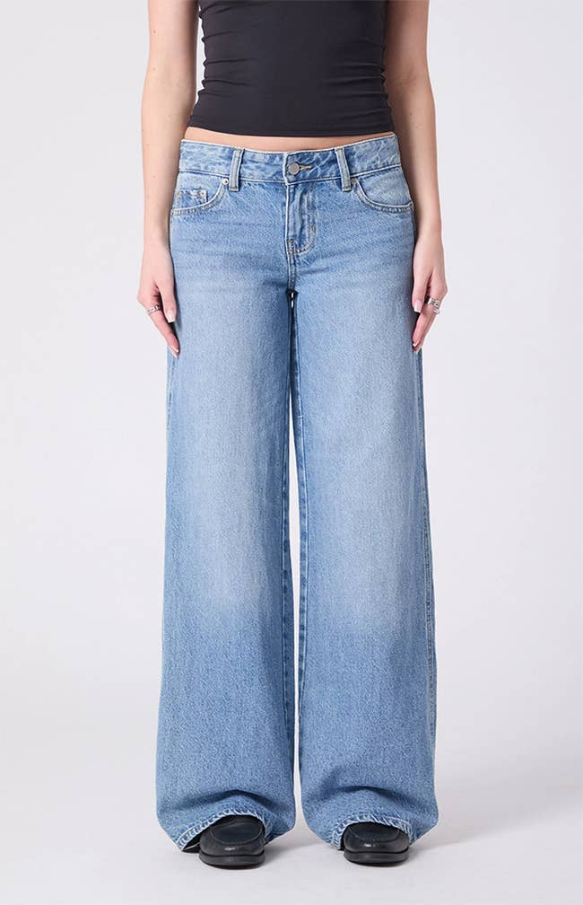 Wide-leg jeans with a precocious waist and classical five-pocket design, paired with a achromatic apical and acheronian shoes