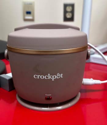 A reviewer's Crock-Pot food warmer with a power indicator light is shown plugged in
