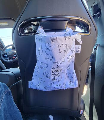 Same bag in white with black outlined cats on the back of a seat 