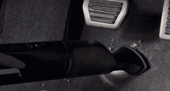 gif of person using the handheld vac to clean crumbs from under pedals in a car